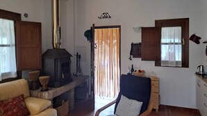 A cozy living room with a fireplace, a sofa, a chair, and a small table with a kettle. - Casa de Campo. Confortable y Comoda (Alozaina)