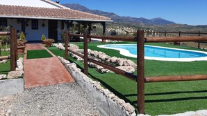 A house with a swimming pool, surrounded by a wooden fence and a paved walkway leading to the entrance. - Casa de Campo. Confortable y Comoda (Alozaina)