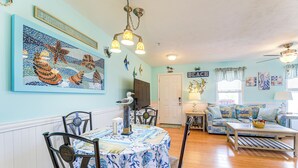 A dining area with a table set for four, a sofa, and a ceiling fan. - Walk to Beach & Pier: Quiet Retreat in Surf City (Surf City)