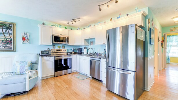 A modern kitchen with white cabinets, stainless steel appliances, and a wooden floor. - Walk to Beach & Pier: Quiet Retreat in Surf City (Surf City)
