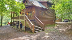 Een houten chalet met een veranda en trap, omringd door bomen.