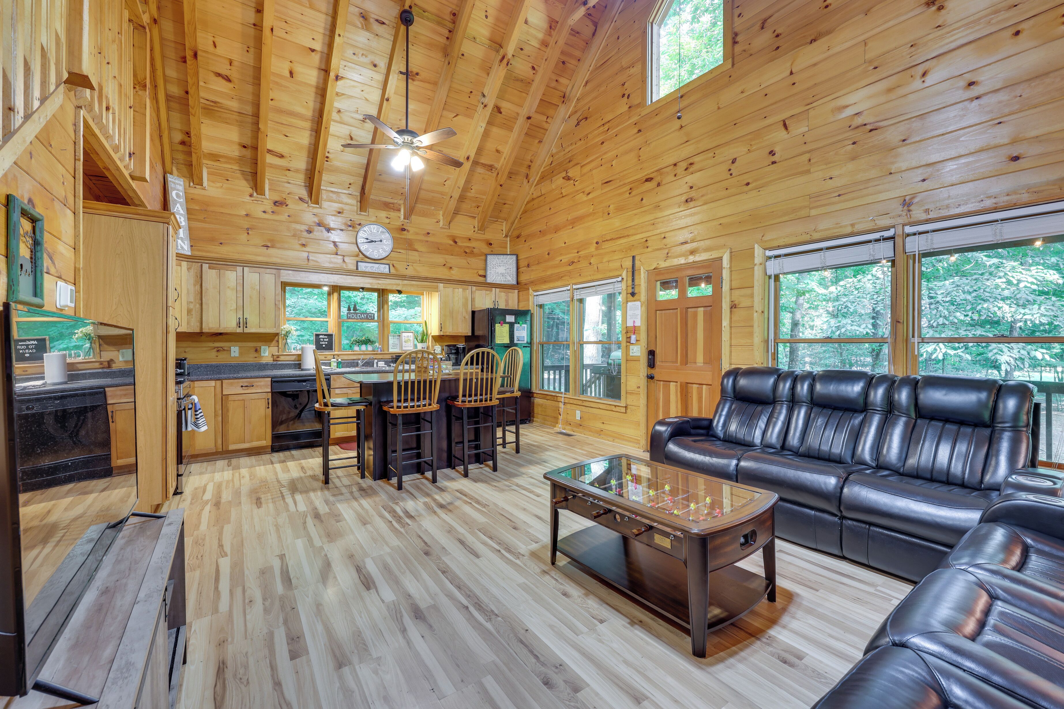 Une cabane en bois spacieuse comprenant un coin repas, une cuisine et un canapé en cuir.