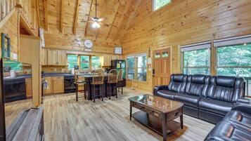 Une cabane en bois spacieuse comprenant un coin repas, une cuisine et un canapé en cuir.