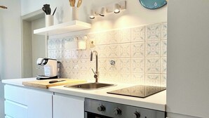 A modern kitchen with a stainless steel sink, a built-in oven, and a clock on the wall. - Vacation home Anni - a retreat to relax and enjoy nature at Lake Tegernsee (Kreuth)