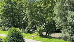 A garden pathway surrounded by lush greenery and trees. - Vacation home Anni - a retreat to relax and enjoy nature at Lake Tegernsee (Kreuth)