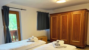 A hotel room with two beds, a wooden wardrobe, and a window with curtains. - Vacation home Anni - a retreat to relax and enjoy nature at Lake Tegernsee (Kreuth)