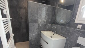 Un bagno moderno con un mobile lavabo bianco, un water e uno spazio doccia.