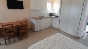 Una camera compatta con un letto, una scrivania e un angolo cottura.
