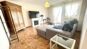 A living room with a sofa, a glass coffee table, a TV, a fireplace, and a lamp.