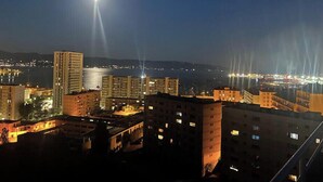 A nighttime cityscape with illuminated buildings and a prominent moon in the sky.
