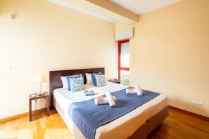 Une chambre d’hôtel avec un lit, une table de chevet, une lampe et une fenêtre avec des stores.