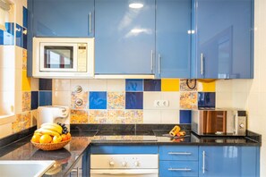 A kitchen with blue cabinets, a microwave, a toaster, and a fruit bowl. - Modern villa with a welcoming atmosphere (Albufeira)