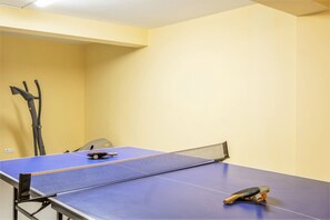 A ping pong table with a net in a room with yellow walls and a ceiling light. - Modern villa with a welcoming atmosphere (Albufeira)