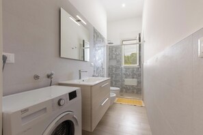 Un baño moderno con lavadora, lavamanos y retrete.