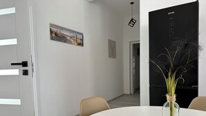 Un intérieur moderne avec une table ronde, des chaises de couleur beige, une porte noire et un tableau encadré au mur.