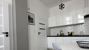 Une cuisine moderne avec des meubles blancs, un plan de travail noir et une table de salle à manger ronde, assortie de chaises.