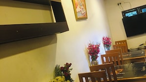 Un comedor con una mesa larga, sillas de madera y centros de mesa con flores.