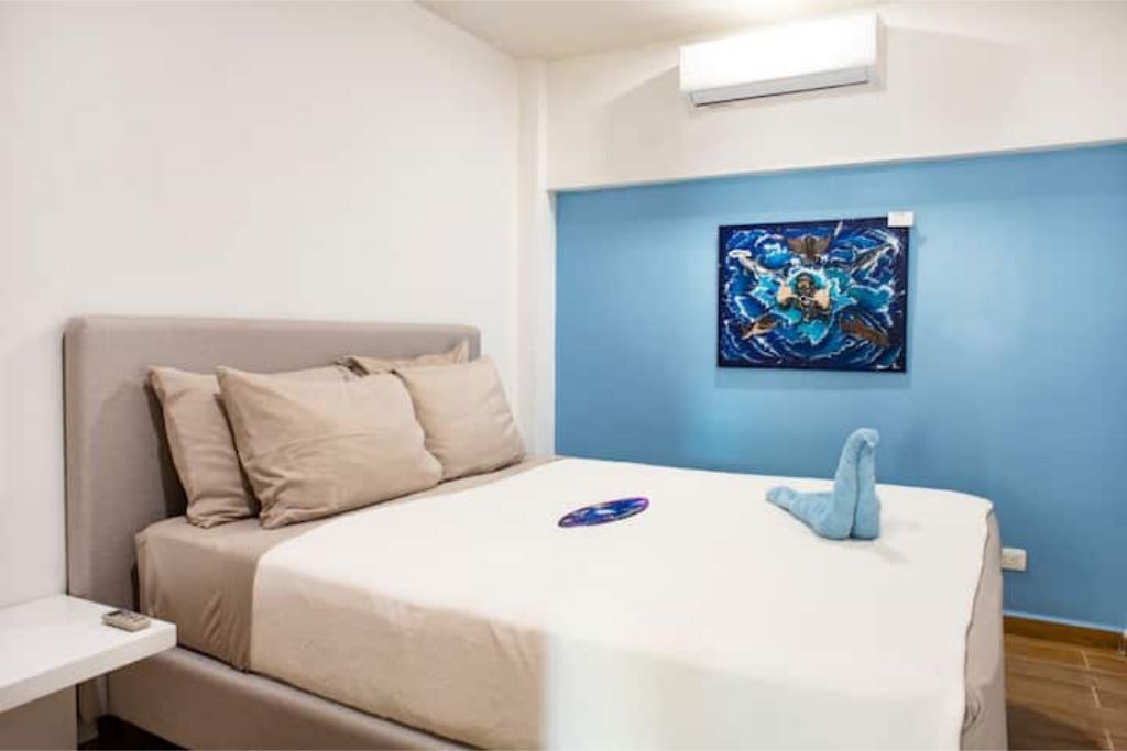 Ein Schlafzimmer mit einem Bett, einem Nachttisch, einer Wandklimaanlage und einem Gemälde.
