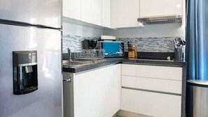 Una cocina moderna con armarios blancos, un refrigerador de acero inoxidable y una encimera azul.