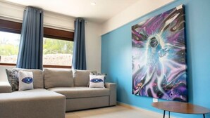 Un salón moderno con un sofá color crema, una mesita redonda y un cuadro abstracto grande en la pared.