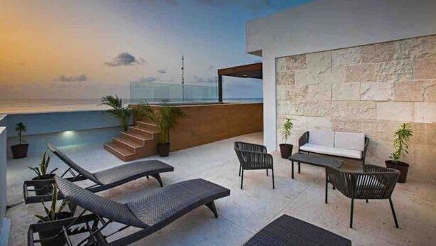 Una terraza en la azotea con sillones, un sofá y plantas en macetas.