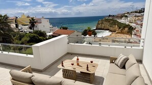 Un balcon avec un canapé, une table basse en bois et une bouteille de vin.