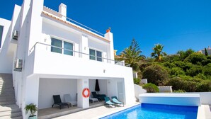 Un bâtiment moderne de couleur blanche, doté d’une piscine, d’un espace extérieur aménagé et d’une bouée de sauvetage.
