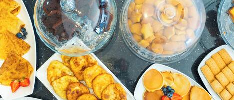 A buffet with various breakfast items including pancakes, biscuits, and a selection of desserts.