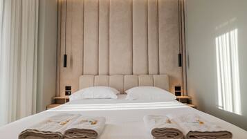 A modern hotel room with a large bed, two bedside tables, and a headboard with vertical panels.