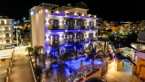 A modern hotel with a pool area, multiple balconies, and a well-lit facade. - Absolute Hotel (Ksamil)