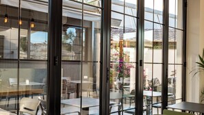A modern indoor dining area with glass partitions, metal-framed tables, and green chairs. - Absolute Hotel (Ksamil)