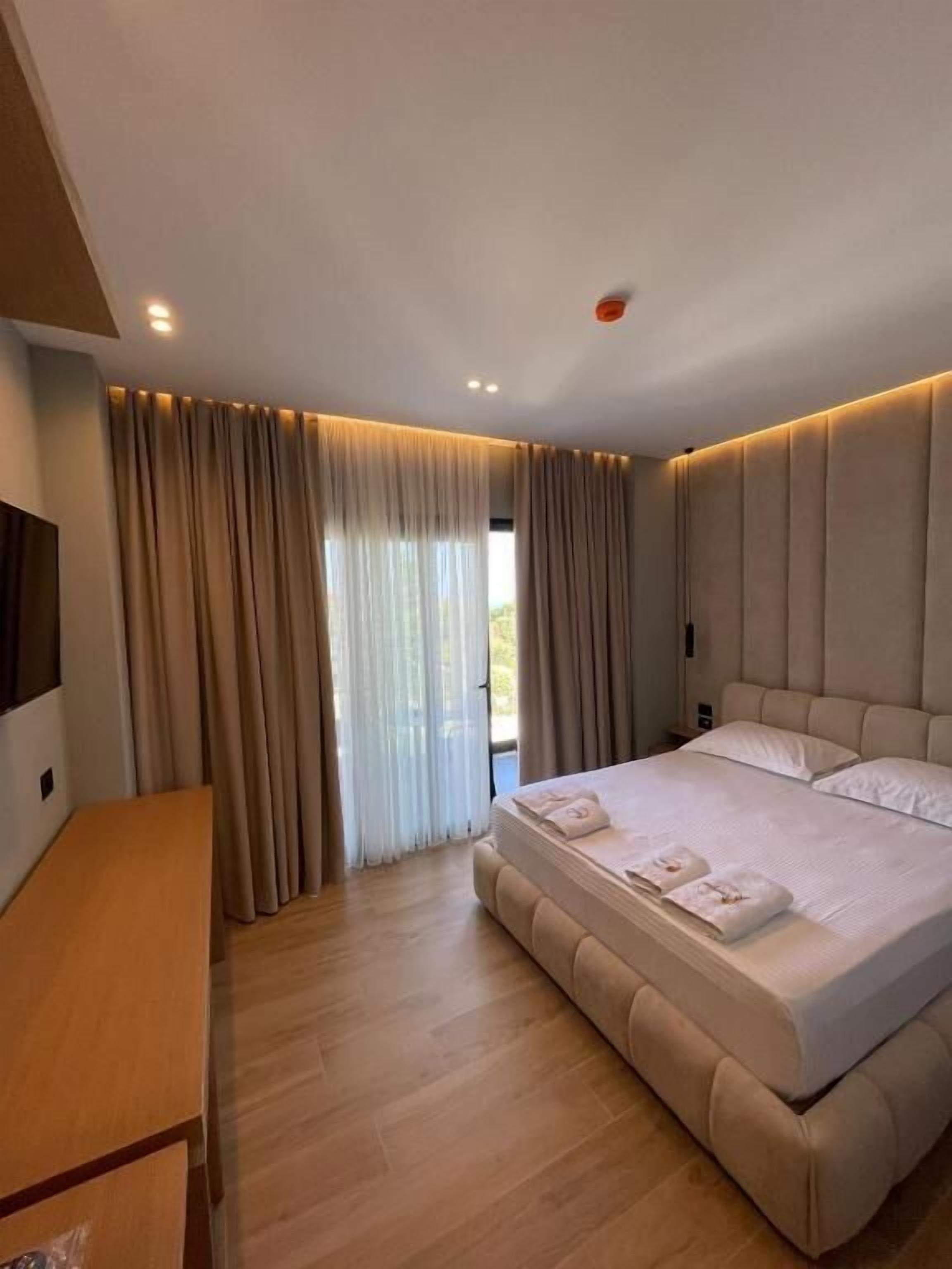 A modern hotel room with a large bed, a flat-screen TV, and a desk.