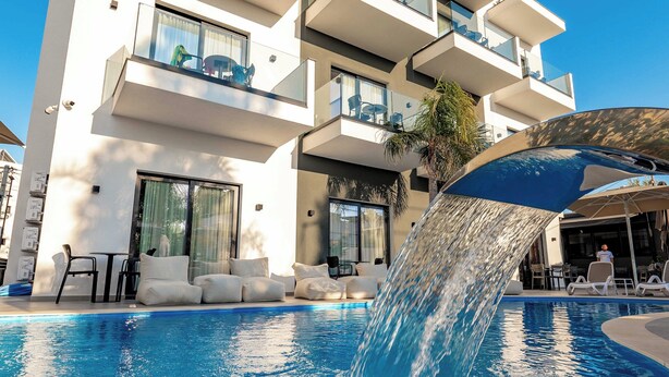 A modern building with a pool featuring a water feature, outdoor seating, and a clear blue sky. - Absolute Hotel (Ksamil)