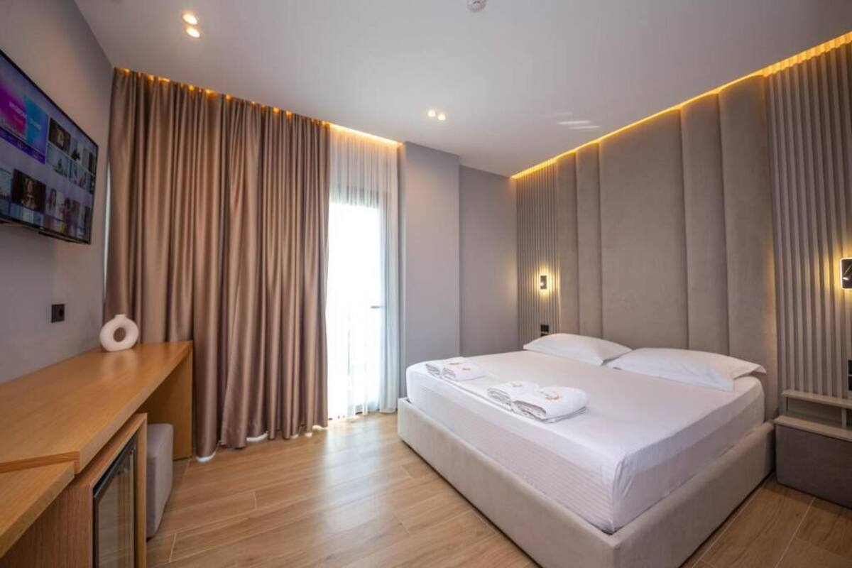 A modern hotel room with a large bed, wooden floor, and a desk with a chair.
