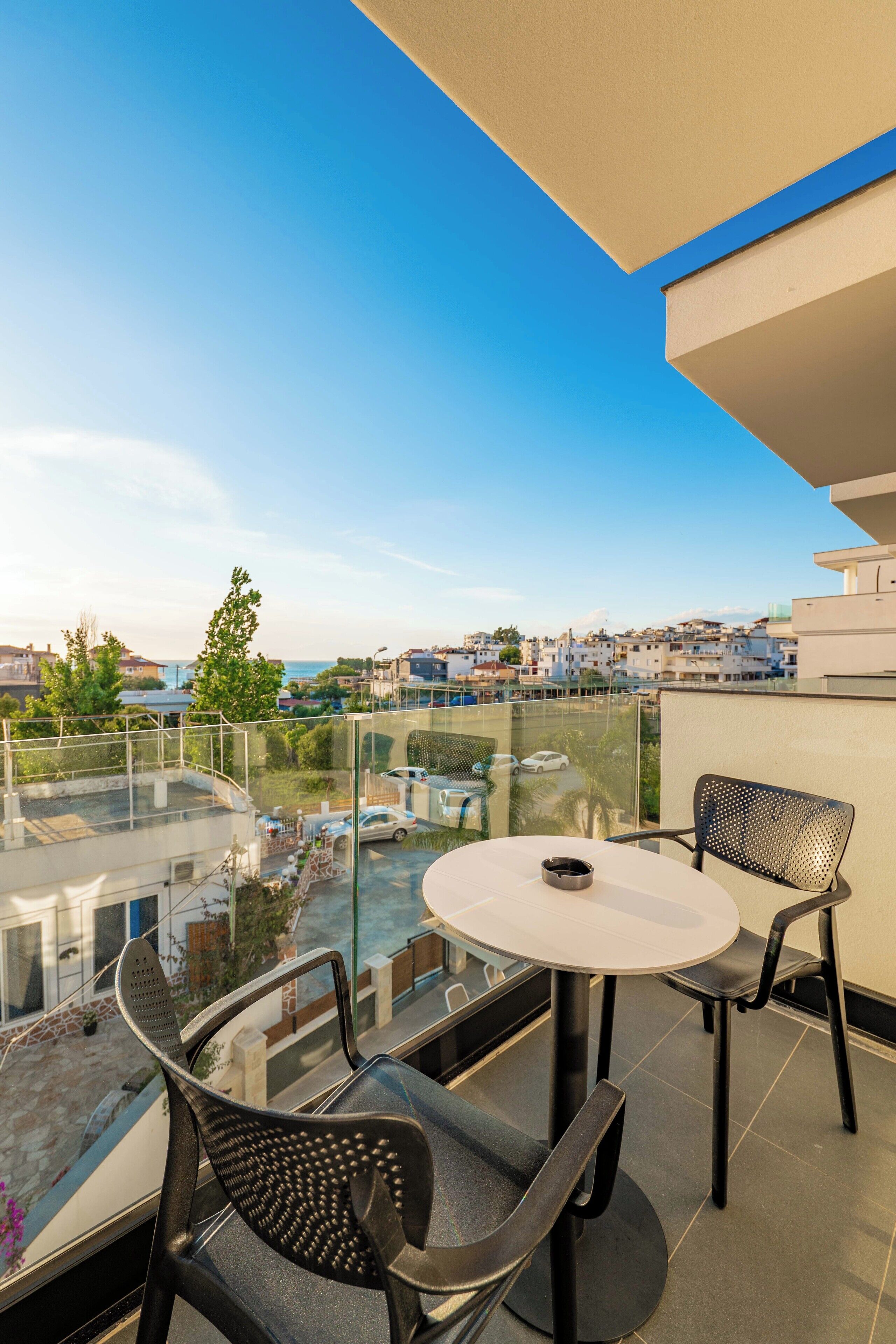 A balcony with a glass railing, a round table, and two chairs.