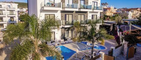 A modern hotel with a rooftop pool, multiple balconies, and a view of the surrounding neighborhood.