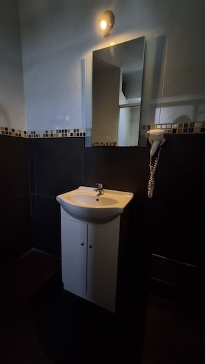 A bathroom with a white sink, a mirror, and a hairdryer. - Platinium Hotel (Tacna)