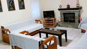 A living room with a sofa, armchairs, a coffee table, a TV, and a fireplace. - Billy s House Vlachava-kalambaka (Kalabaka)