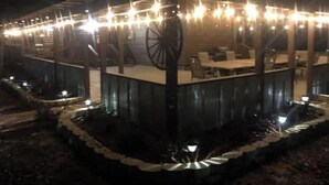 An outdoor restaurant with a covered seating area, tables, and a large wheel structure.