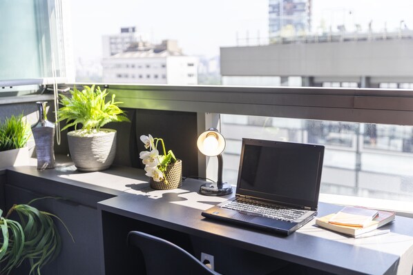 A desk with a laptop, a desk lamp, and potted plants.