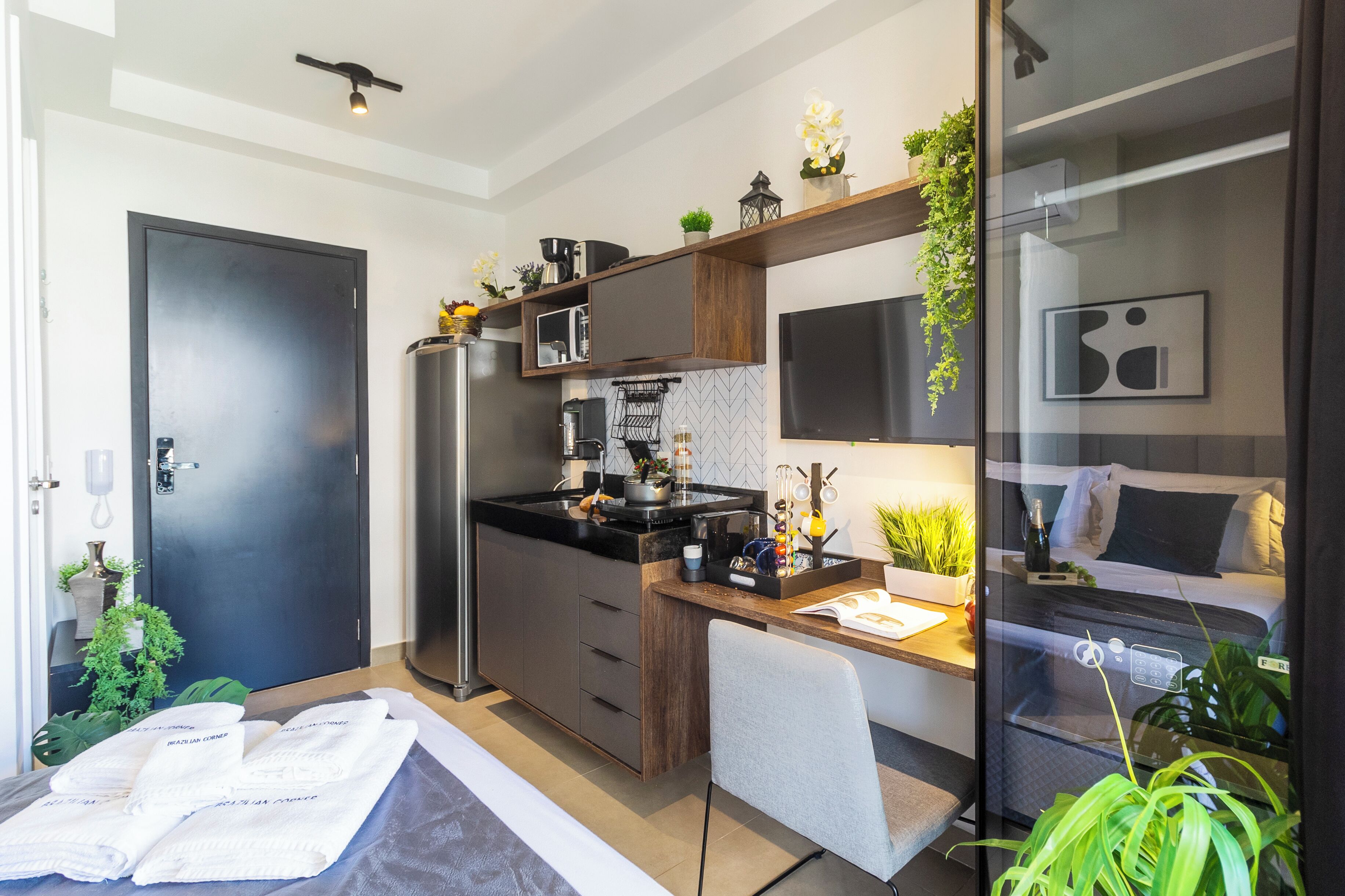 Una habitación de hotel compacta con kitchenette, una cama, un escritorio y una zona de estar.