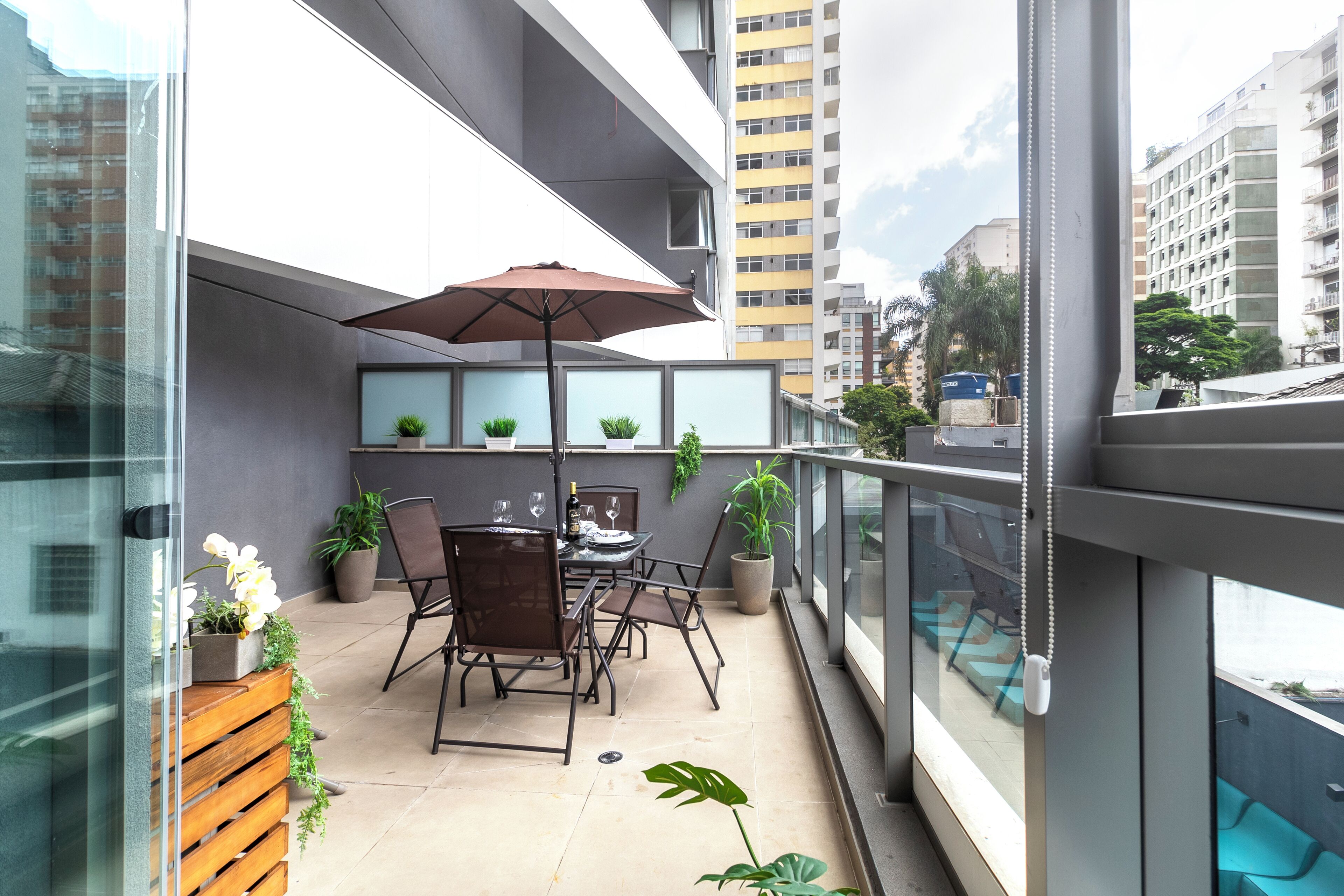 Ein Balkon mit Tisch, Stühlen, Topfpflanzen und Blick auf die Stadt.