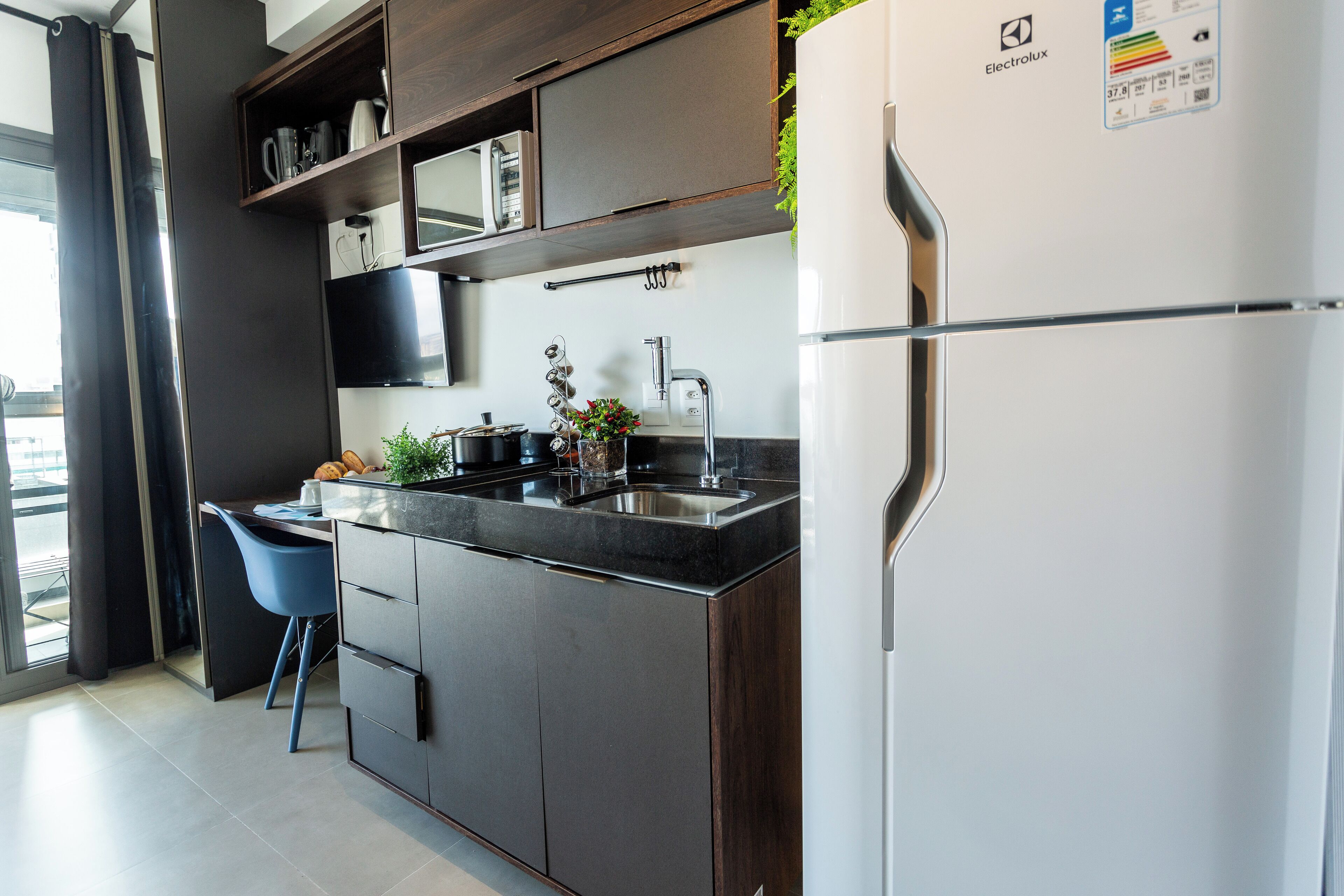 A modern kitchen with dark wood cabinets, a white refrigerator, and a blue chair.