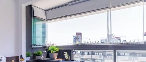 Une chambre moderne avec un lit, un bureau et un balcon offrant une vue sur la ville.