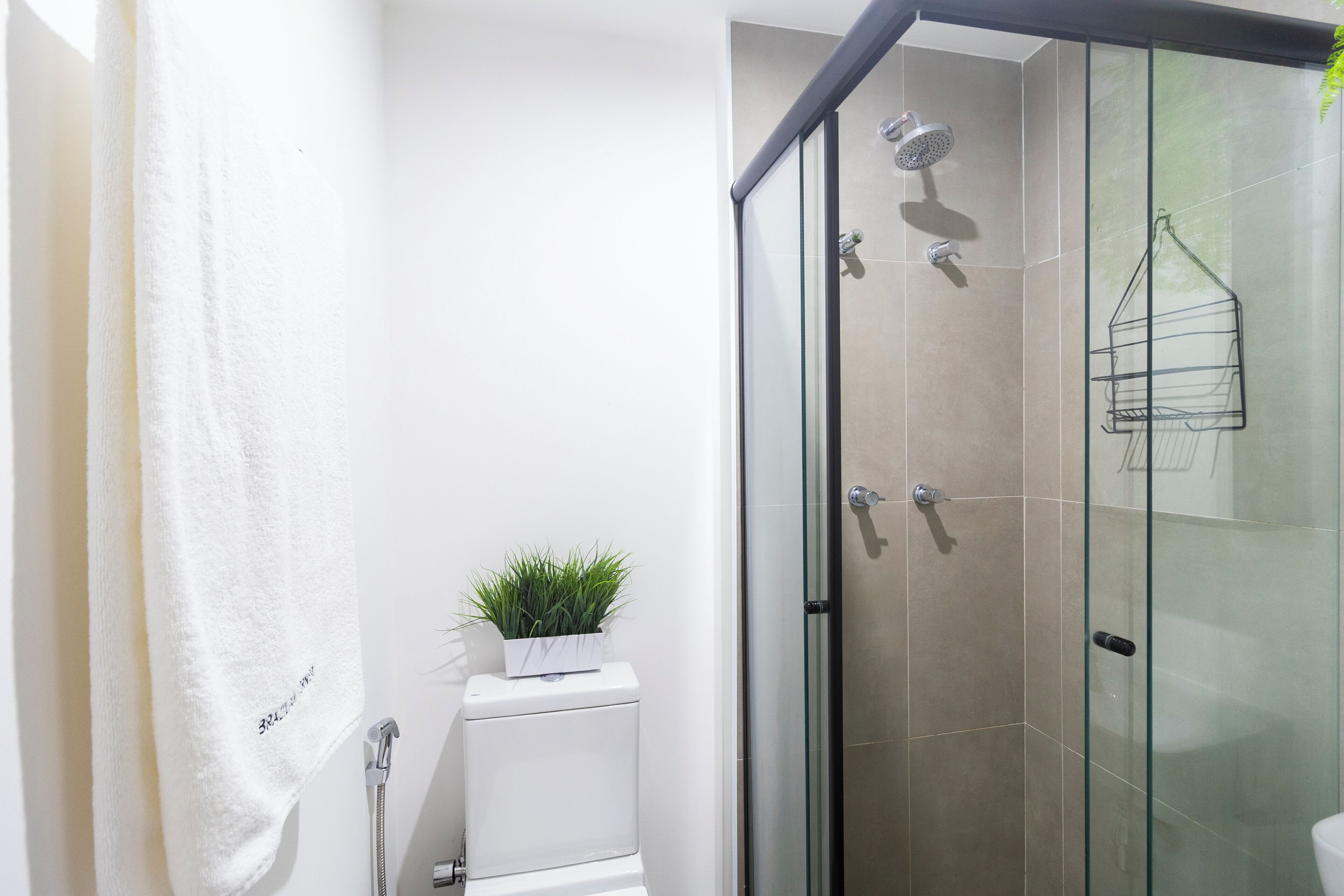 A modern bathroom with a glass shower enclosure, a white toilet, and a towel hanging on a rack.