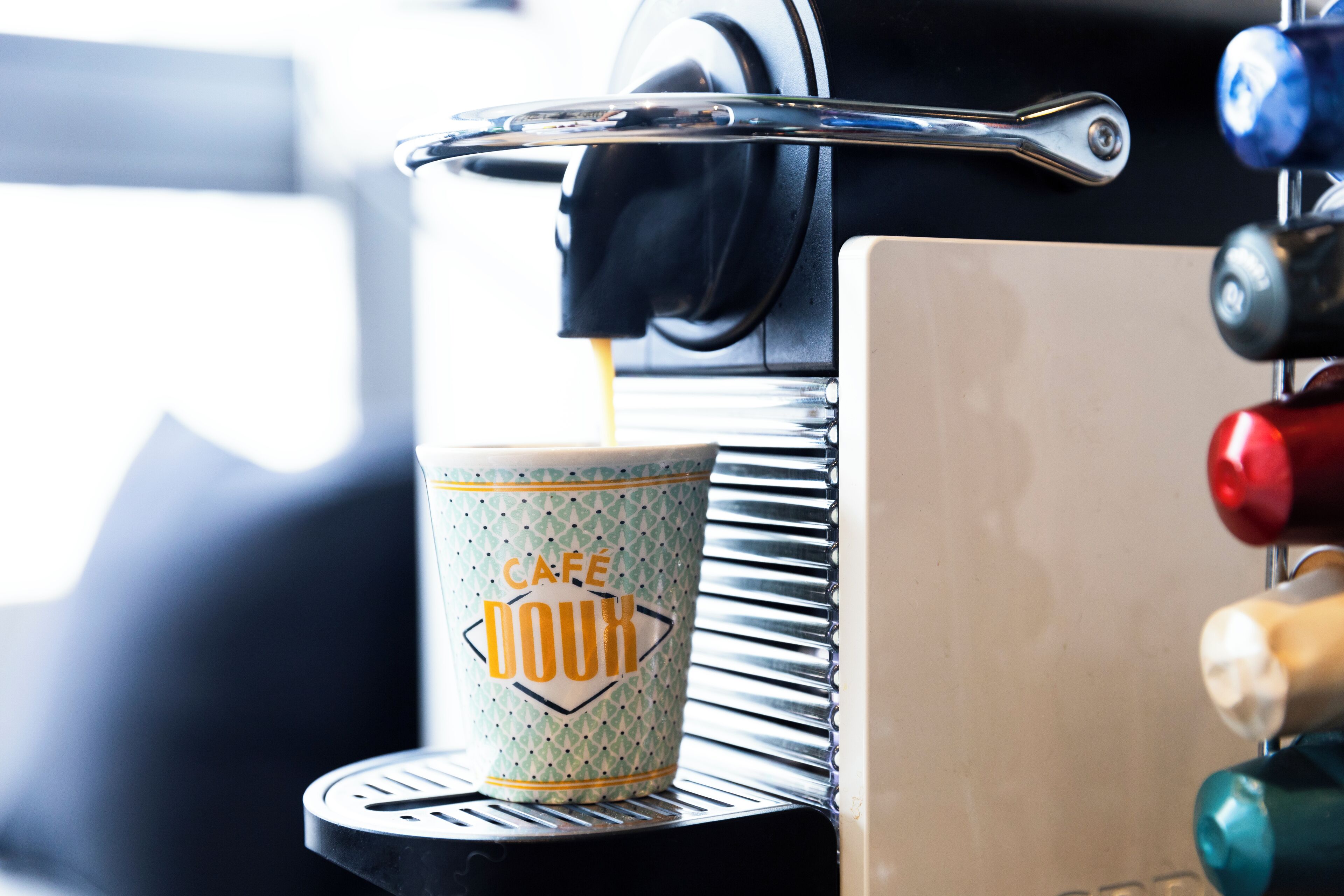 A coffee machine dispensing coffee into a cup labeled "Café Doux."