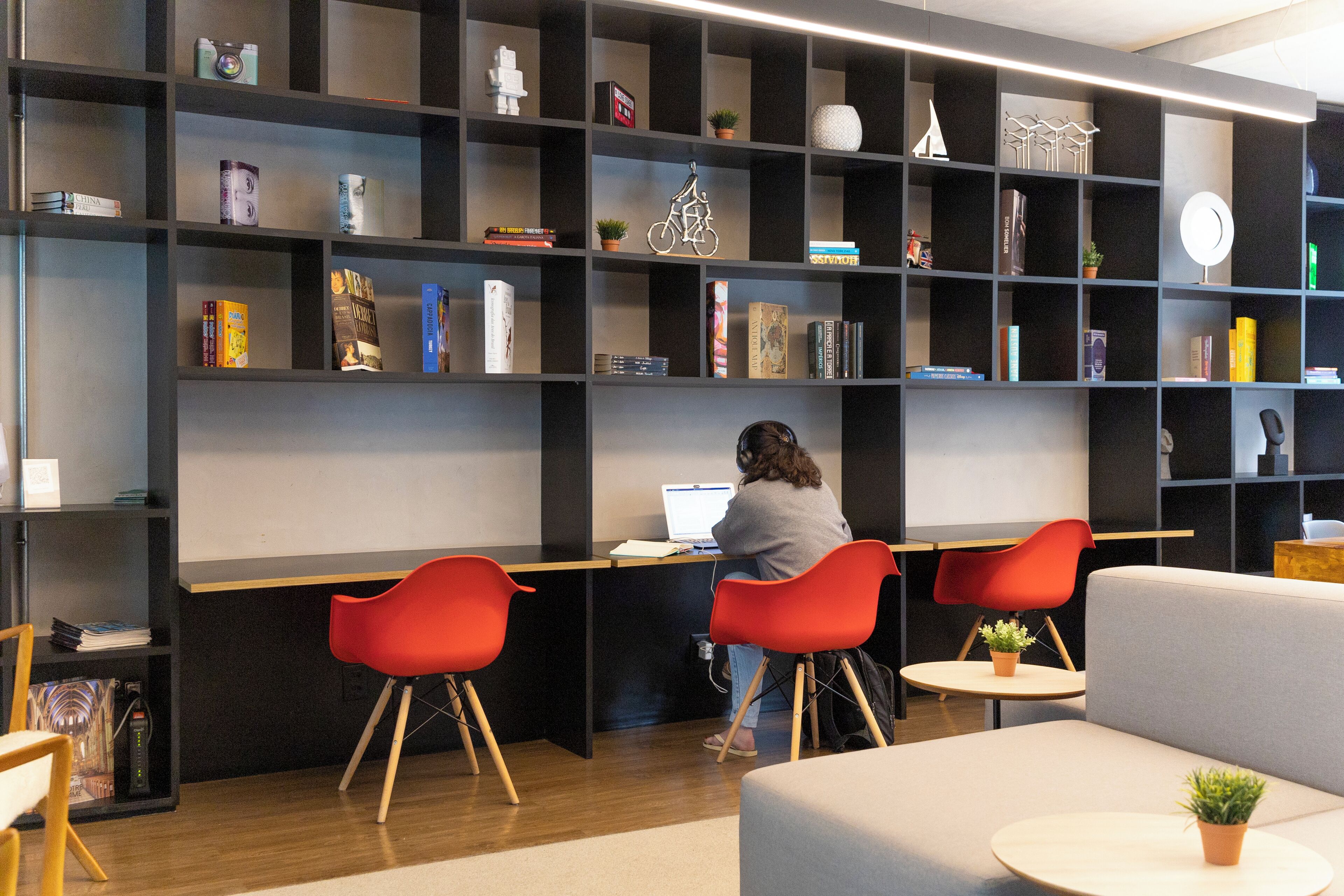 Eine moderne Bibliothek mit mehreren Regalen, einem Schreibtisch und roten Stühlen.