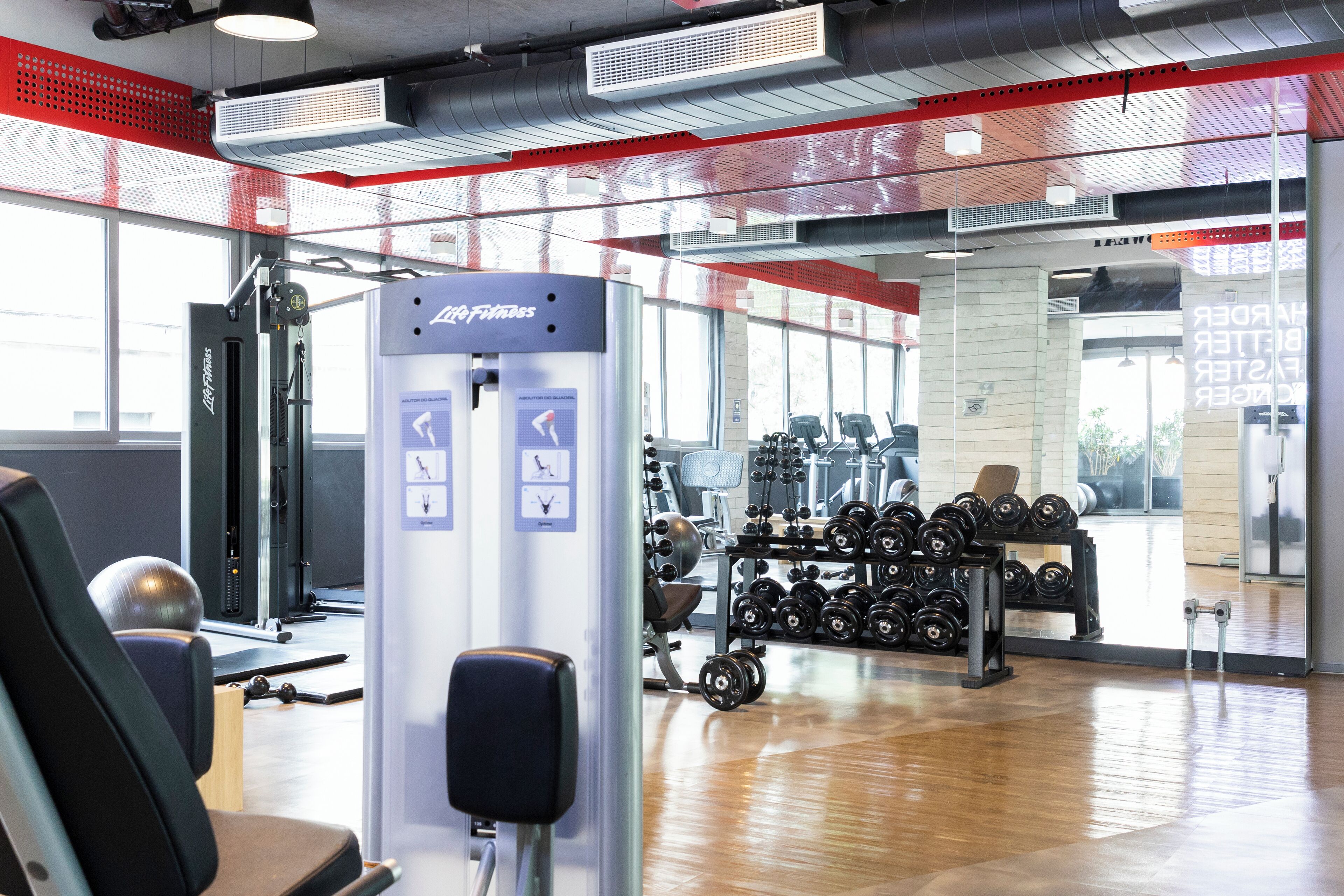 Ein Fitnessraum mit Trainingsgeräten, Gewichtsständern und einer Spiegelwand.