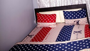 A bed with a patterned bedspread, a framed picture on the wall, and a window with curtains. - Smilley's Place Cosy accommodation close to Unilag (Lagos)