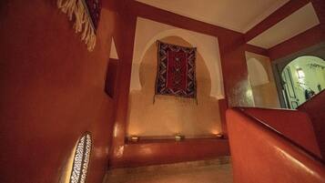 A staircase with a red wall and a patterned tapestry.